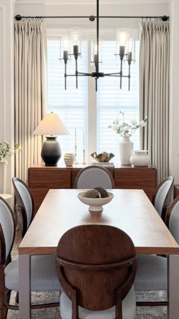Modern dining room with large windows styled with neutral floor-length curtains that filter natural light.