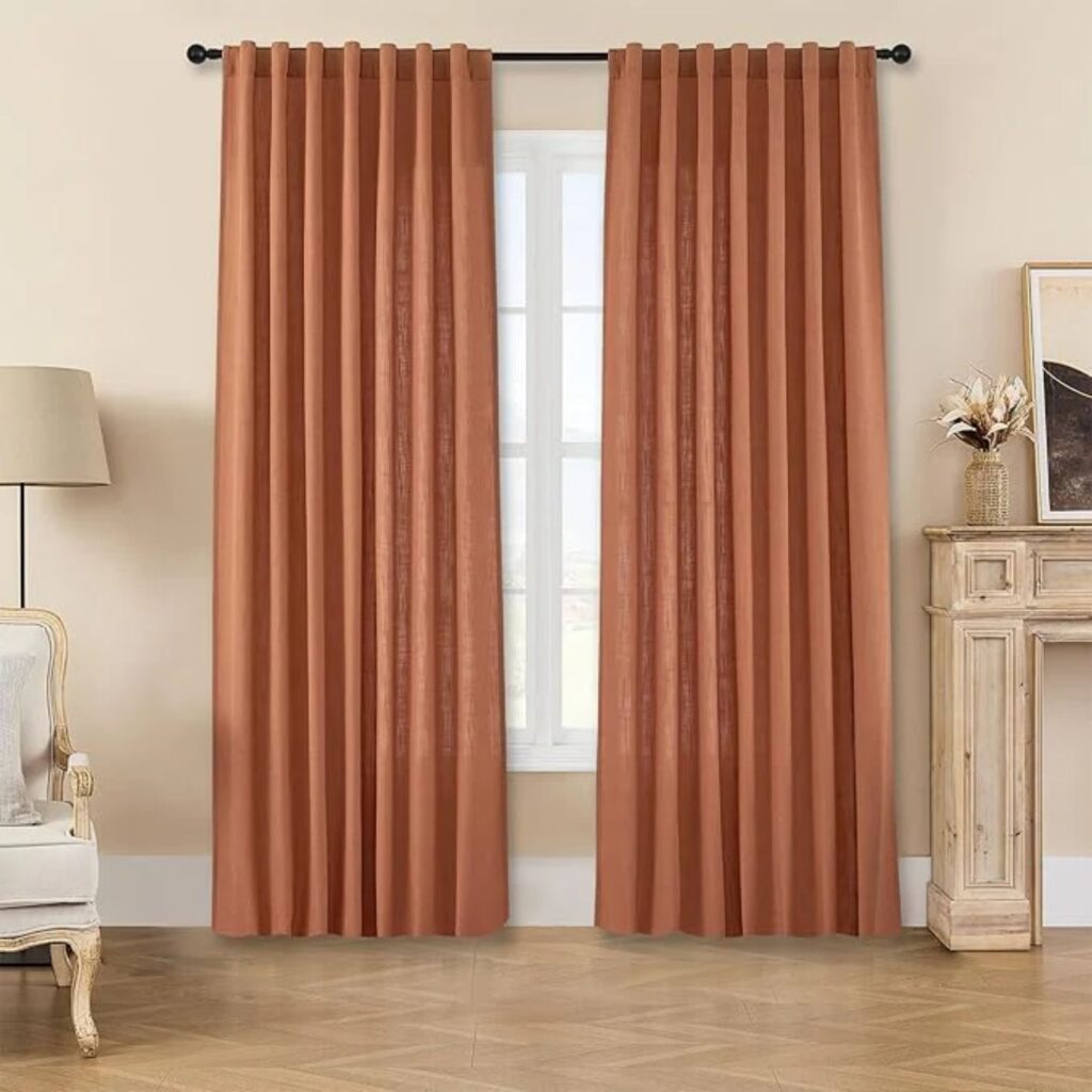 Joydeco Window Treatments in Burnt orange blackout curtains framing a window in a neutral interior.