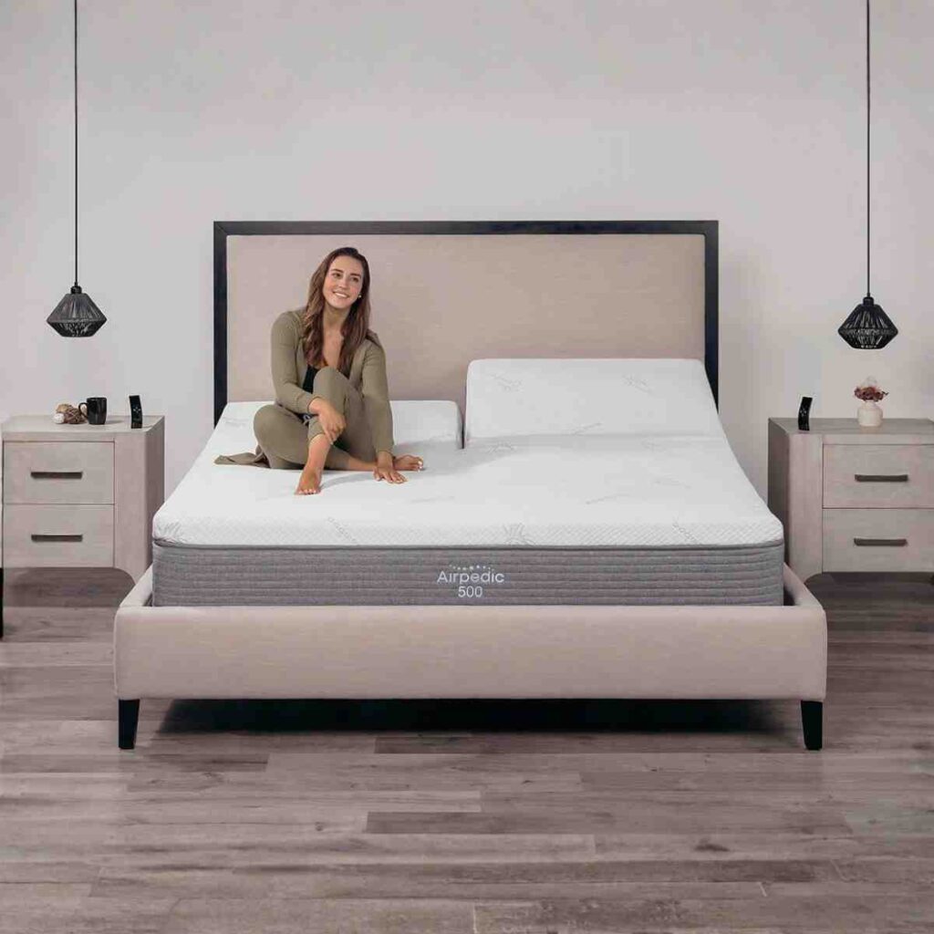 Woman in white pajamas sitting on an Airpedic 500 mattress with the head raised