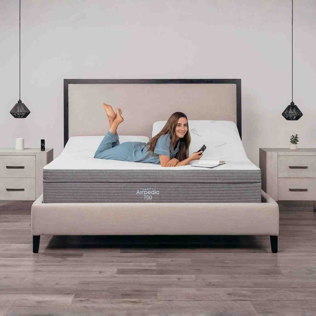 Woman lying on an Airpedic 700 flat mattress looking at her smartphone.