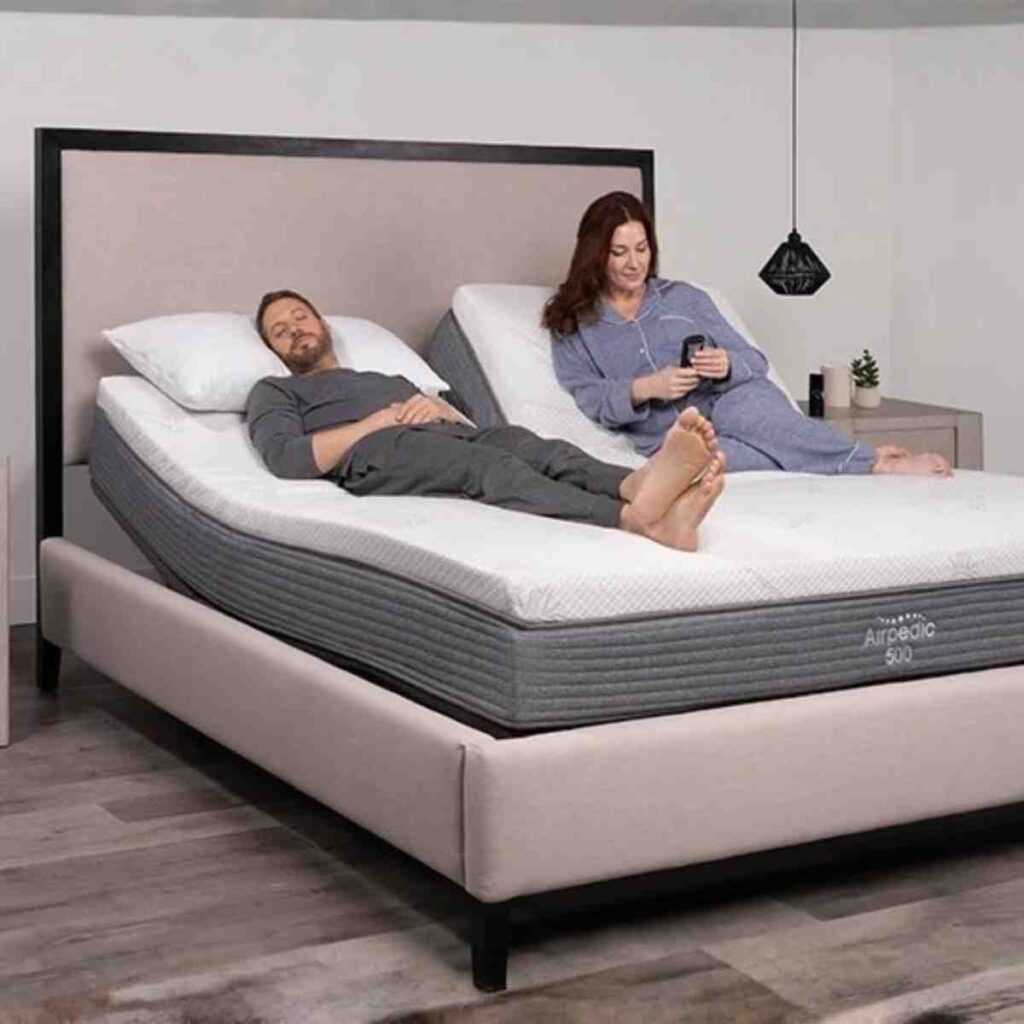 A couple enjoying the Airpedic dual-zone adjustable bed in a modern taupe bedroom for individualized sleep comfort.