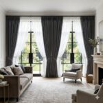 The CurtainUK Collection: Luxury Drapery for Every Room 5 Floor-to-ceiling charcoal grey blackout curtains layered with white sheer drapes on large windows in a modern UK living room.