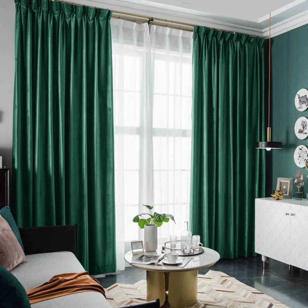 Emerald green velvet custom blackout curtains framing a large living room window for a luxury aesthetic.