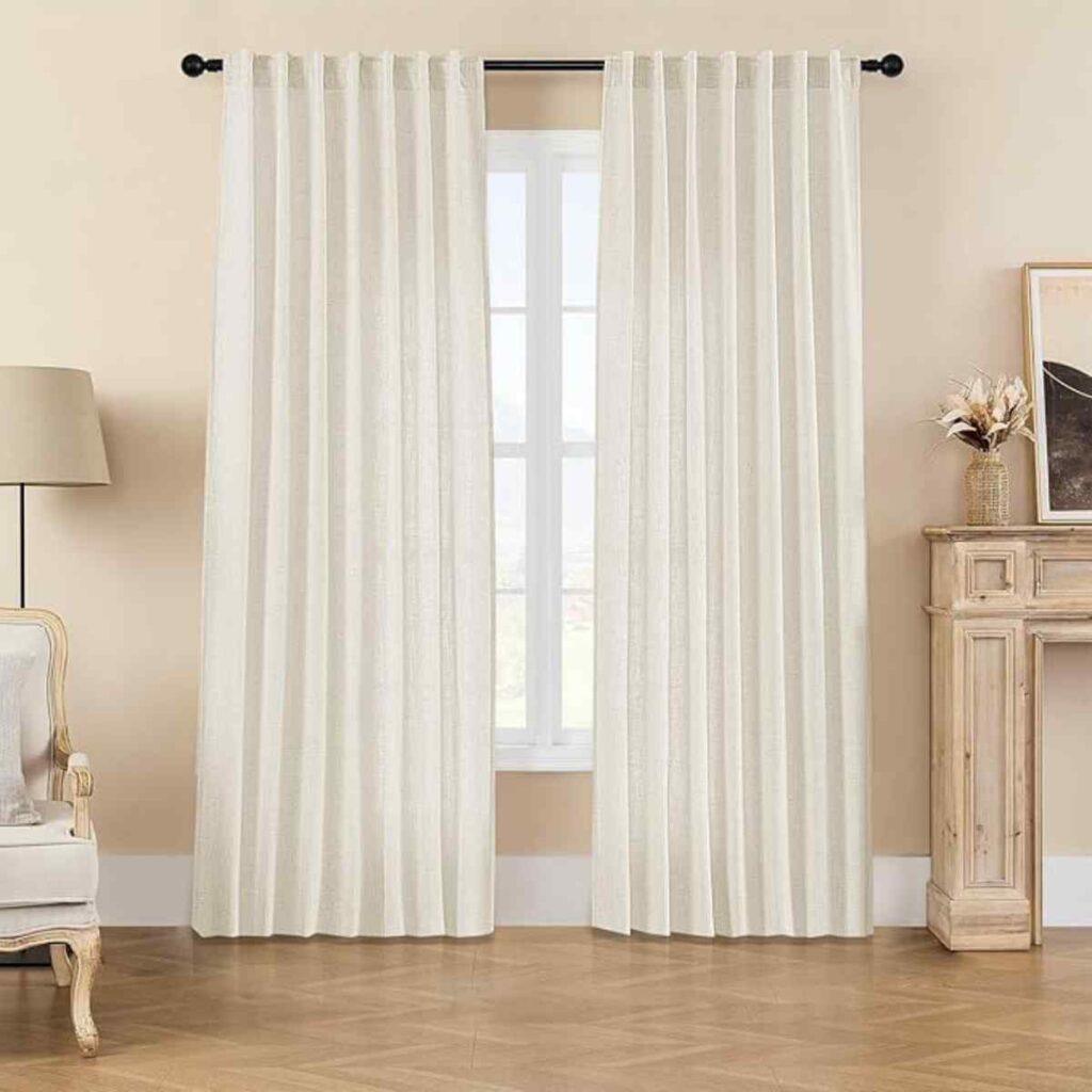 Beige Joydeco linen-textured sheer curtains on a large window in a bright living room.