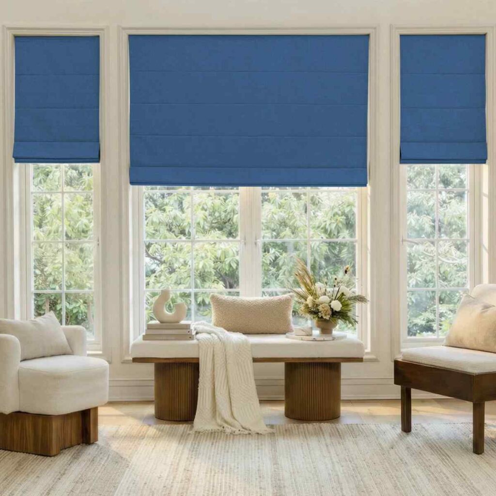 Three blue Joydeco Roman shades installed in a bright living room with a modern rug.