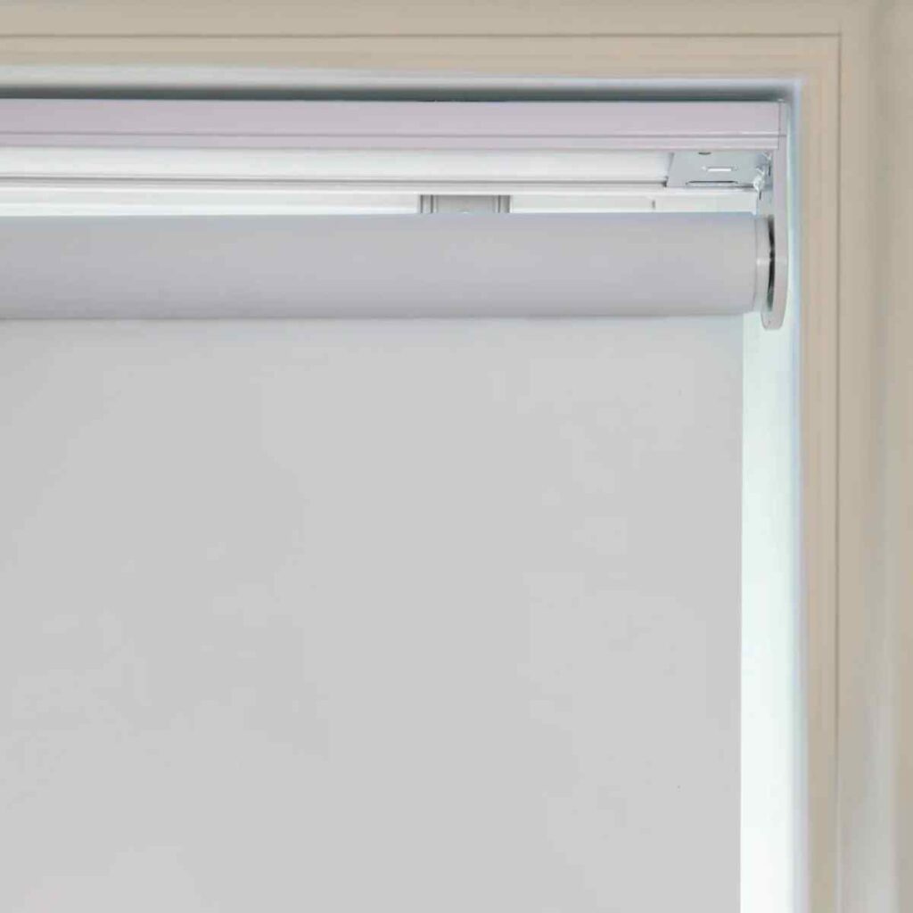 Grey Joydeco cordless roller shade installed inside a window frame for a minimalist look.