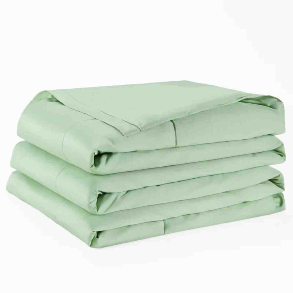 A folded Promeed mulberry silk-filled quilt in light sage green.