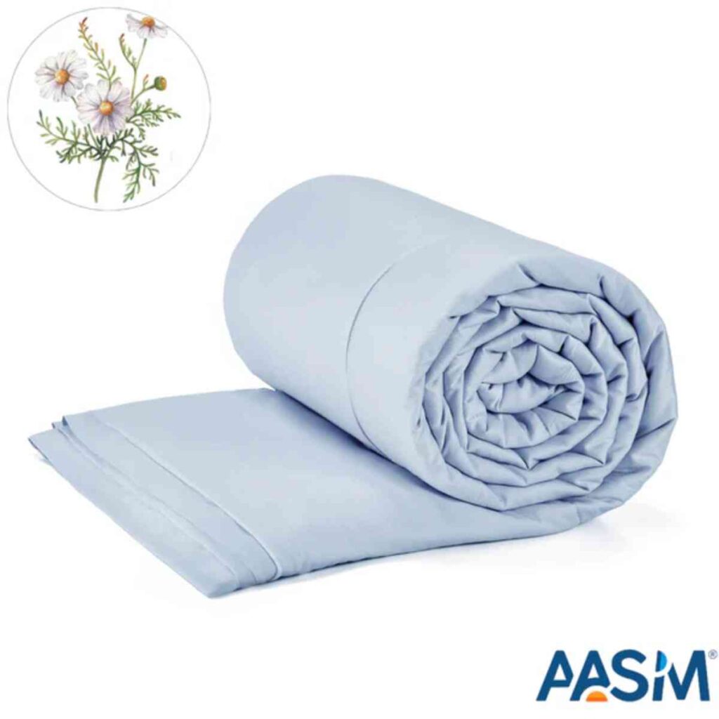 A lightweight light blue Promeed silk quilt neatly folded on a bed, showcasing its smooth texture and summer-ready design.