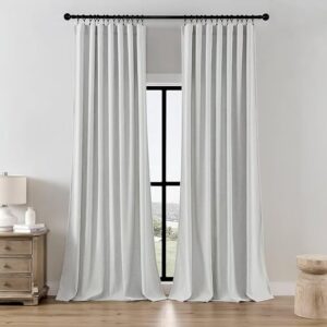 Pair of elegant greyish white linen curtains hung with black clip rings on a black rod framing a tall window in a bright bedroom.