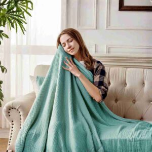 Joydeco Sage Green 100% Cotton Muslin Throw Blanket draped on a sofa.