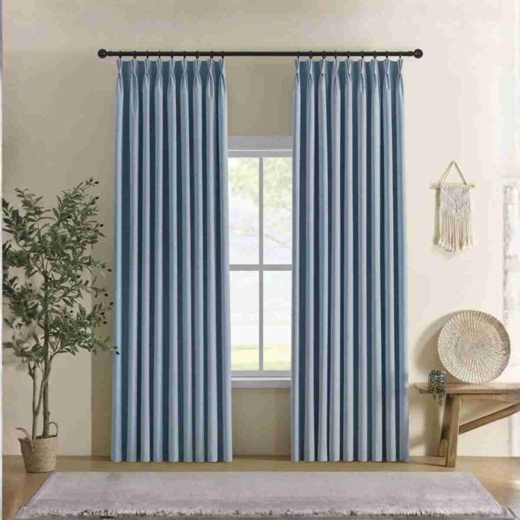 Elegant blue linen blackout curtains with refined modern look Elegant light blue pinch-pleat linen drapes as modern custom window treatments in a bright living room with a black curtain rod and indoor plant.