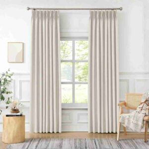 Sophisticated pinch pleat linen drapes in white, featuring a structured pleated top and a luxurious textured finish in a sunlit room.