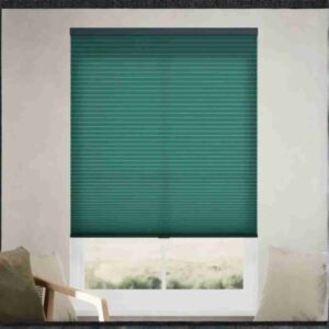 Modern emerald green cellular shades with a honeycomb texture installed on a window in a bright, minimalist living room.
