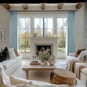 Luxury sea foam linen pleated curtains with tailored pinch pleats framing a large window in a bright living room with white sofas.