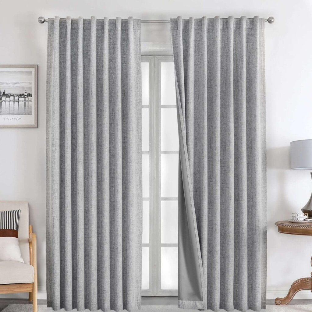 A perfectly styled layout showing light grey linen curtains hanging by a window in a contemporary interior.