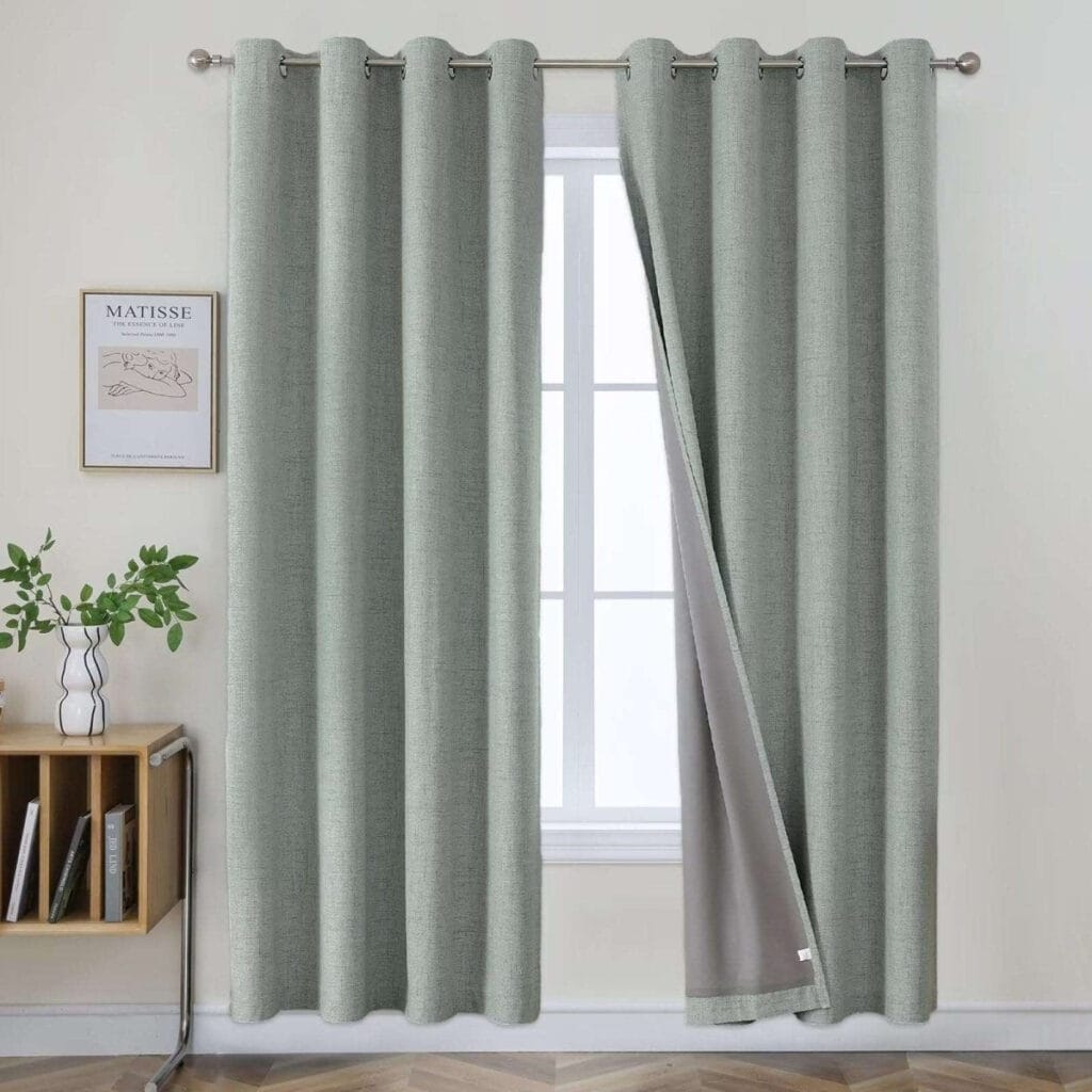 Close-up fabric details highlighting a high-quality set of sage green linen curtains draped in a modern bedroom.