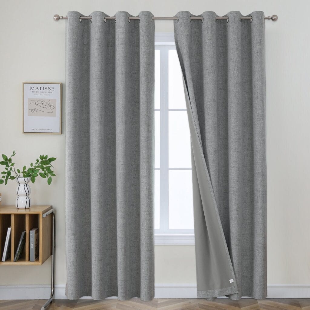 Joydeco 100% blackout faux linen curtains in blackout linen light grey hanging beautifully in front of a window.
