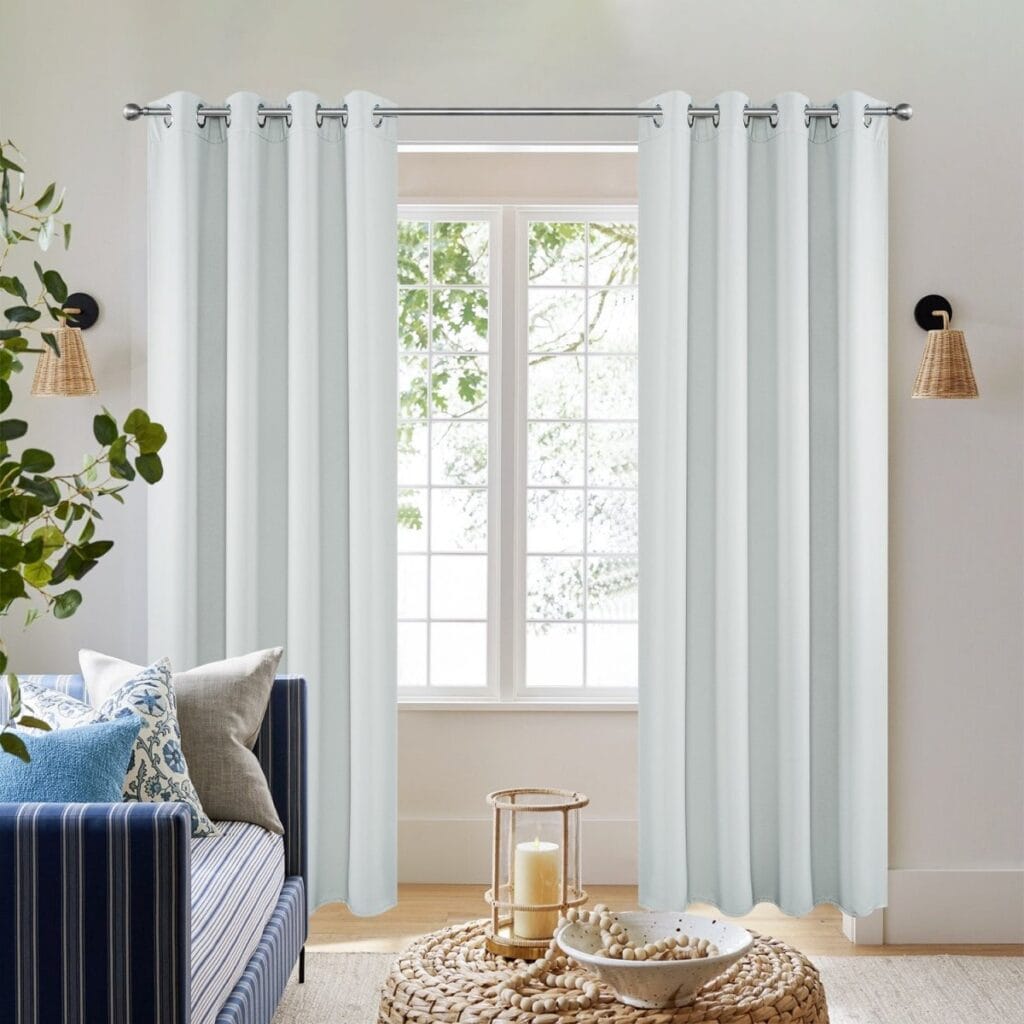 Stylish joydeco blackout greyish white sun-blocking drapes hanging gracefully next to a decorated side table.