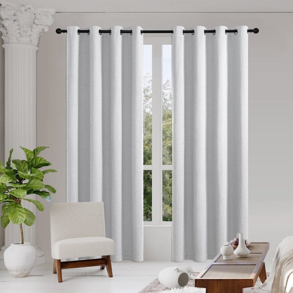 A bright living room space displaying elegant thermal curtains off white hanging beautifully by a modern window layout.