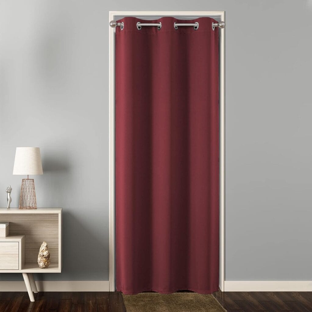 A wide residential patio door dressed beautifully with custom extra wide burgundy curtains in a sunlit dining area.