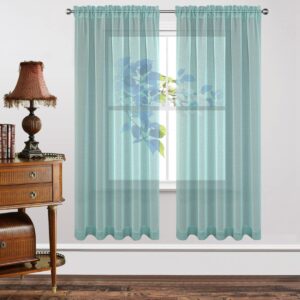 Bright contemporary window frame accenting the beautiful design of teal blue sheer curtains letting in soft natural light.