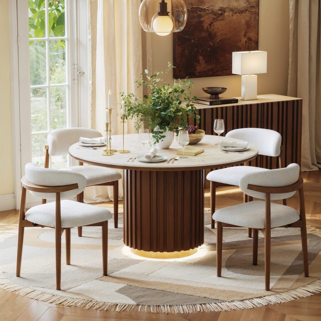 Round dining table featuring a faux travertine round dining table top and fluted pedestal base.