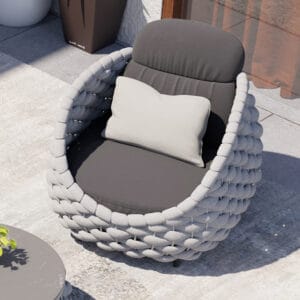 Relaxed outdoor lounging on a Cocaro outdoor swivel lounge chair with hand-woven rope.