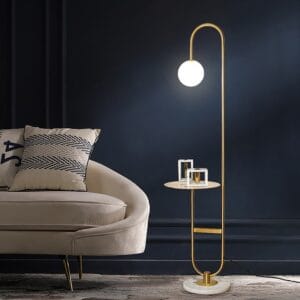 Curved and angled modern floor lamp with shelf featuring a marble base and metal frame.